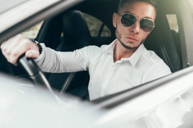 Lüks aracın içinde oturan yakışıklı genç adam