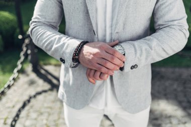 Sakallı ve güneş ışığı altında sokakta şık takım elbise poz içinde gözlüklü genç adam