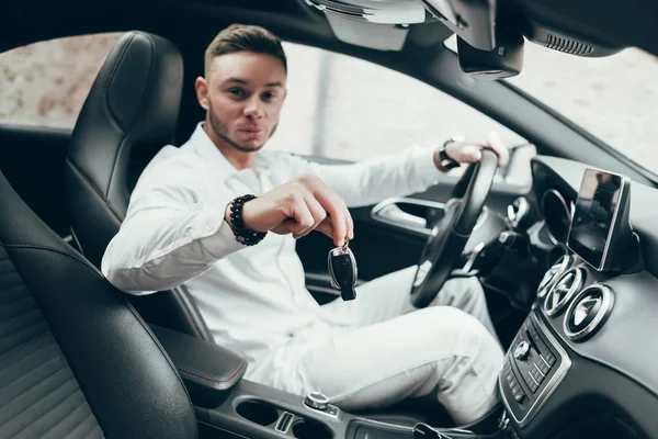 Yakışıklı genç adam onun yeni araba anahtarları gösterilen lüks aracın içinde oturan Auto satın