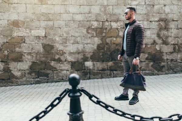 Sakallı ve güneş ışığı altında sokakta şık kıyafet poz içinde gözlüklü genç adam