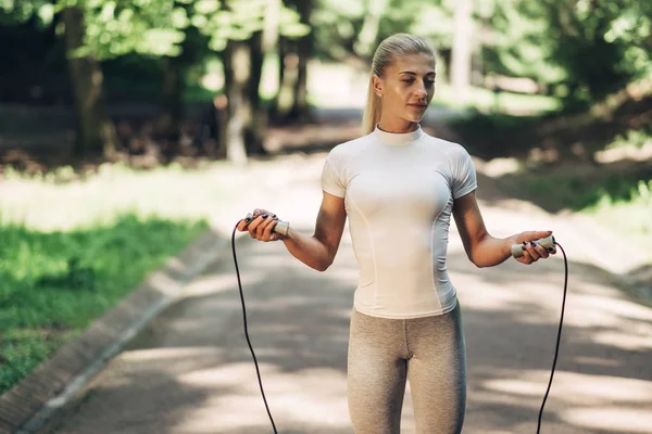 Park ip atlama ile uygun genç kadın portresi. Fitness erkek güneşli günde Park açık havada egzersiz yapıyor.