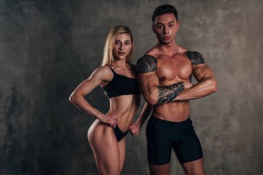 Atletik fitness çift. Gömleksiz vücut geliştirmeci ve fitness kız arkadaşı.