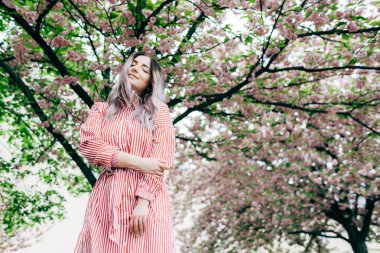 Park güneşli günde kiraz çiçeği mevsiminde zevk güzel genç kadın