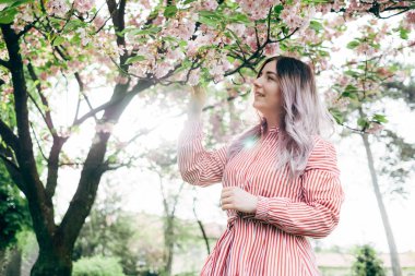 Park güneşli günde kiraz çiçeği mevsiminde zevk güzel genç kadın