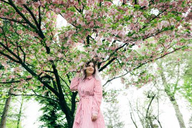 Park güneşli günde kiraz çiçeği mevsiminde zevk güzel genç kadın