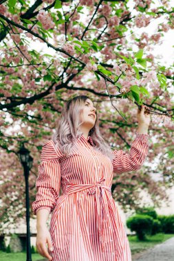 Park güneşli günde kiraz çiçeği mevsiminde zevk güzel genç kadın