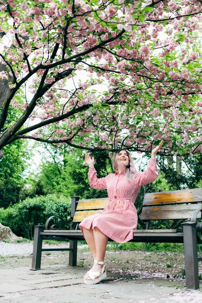 Park güneşli günde kiraz çiçeği mevsiminde zevk güzel genç kadın