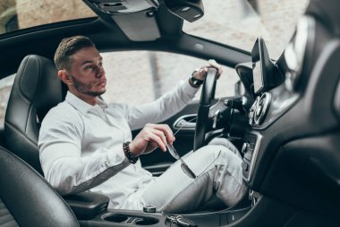 Lüks aracın içinde oturan yakışıklı genç adam