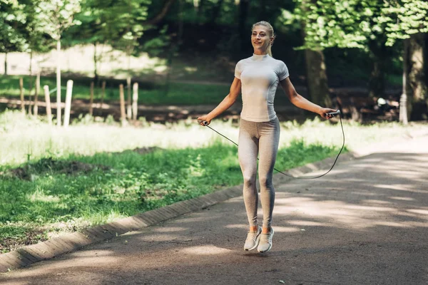 Park ip atlama ile uygun genç kadın portresi. Fitness erkek güneşli günde Park açık havada egzersiz yapıyor.