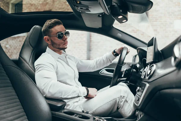 Lüks aracın içinde oturan yakışıklı genç adam