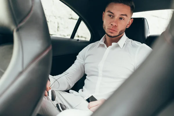 Handsome businessman sitting in luxury car on the back seat