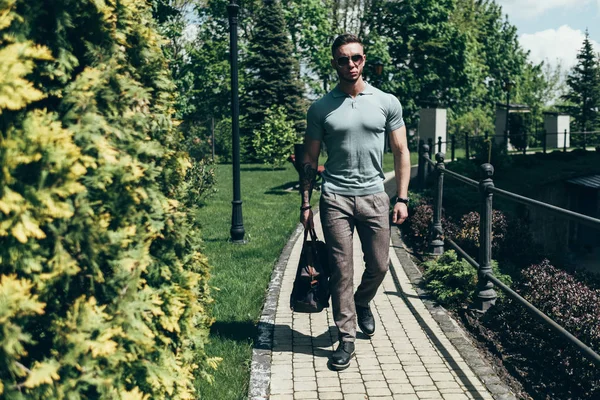 Sakallı ve güneş ışığı altında sokakta şık kıyafet poz içinde gözlüklü genç adam