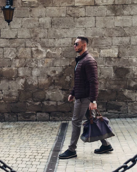 Sakallı ve güneş ışığı altında sokakta şık kıyafet poz içinde gözlüklü genç adam