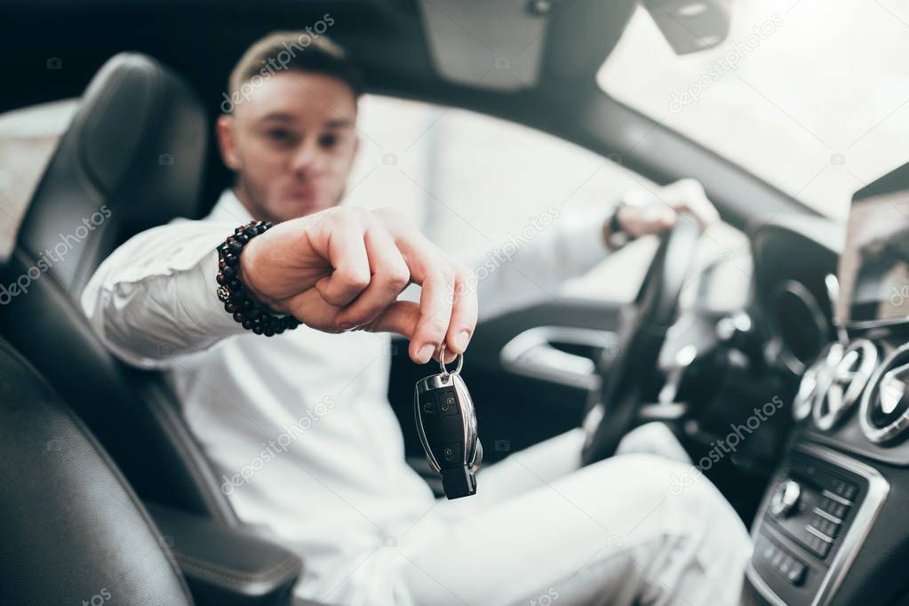 Handsome Young Man Showing Car Keys in His Newly Bought Auto Sitting in the Luxury Vehicle