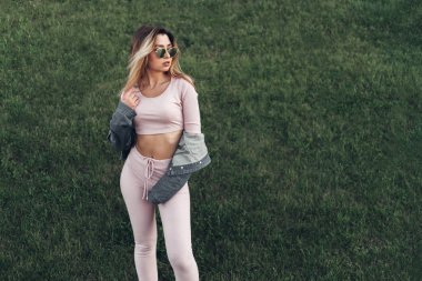 Genç ve güzel kadın sokakta rahat kıyafetler portresi. Pembe gömlek ve pantolon giymiş. Bahar, yaz konsepti. Zaman rahatla. Güneş gözlüklü kız. Şehir Günbatımı keyfini çıkarın.