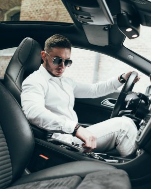 Lüks aracın içinde oturan yakışıklı genç adam