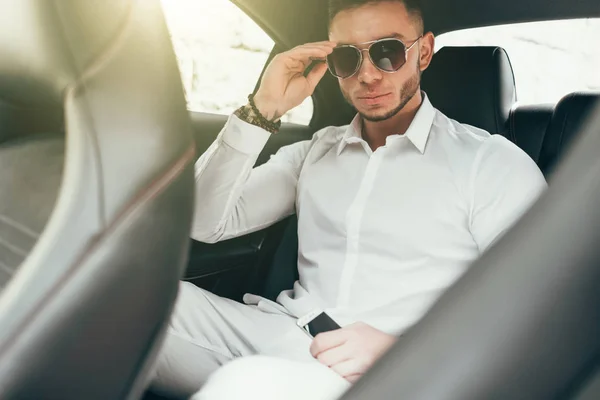 Handsome businessman sitting in luxury car on the back seat