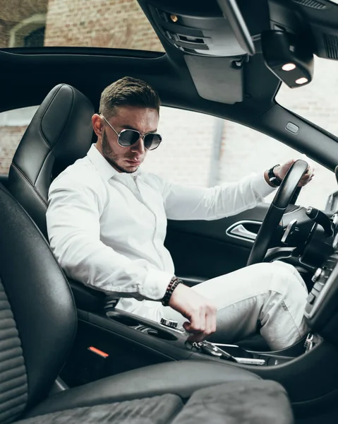 Lüks aracın içinde oturan yakışıklı genç adam