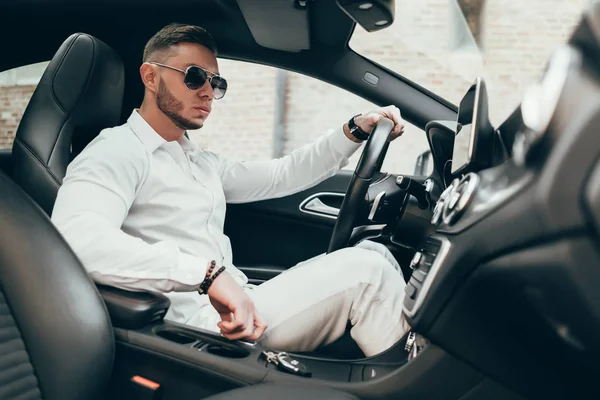 Lüks aracın içinde oturan yakışıklı genç adam