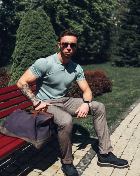 Sakallı ve güneş ışığı altında sokakta şık kıyafet poz içinde gözlüklü genç adam