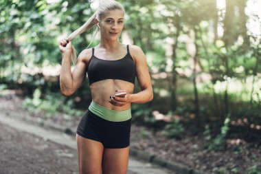 Smartphone cep telefonu ile Bluetooth kulaklık kullanarak müzik dinlemek kadın Runner yaz sabah parkta. Kadın kız dışında yolda koşu.