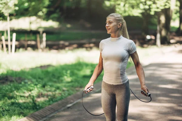 Park ip atlama ile uygun genç kadın portresi. Fitness erkek güneşli günde Park açık havada egzersiz yapıyor.