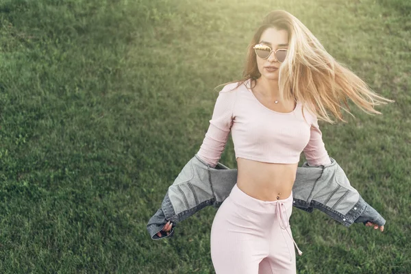 Genç ve güzel kadın sokakta rahat kıyafetler portresi. Pembe gömlek ve pantolon giymiş. Bahar, yaz konsepti. Zaman rahatla. Güneş gözlüklü kız. Şehir Günbatımı keyfini çıkarın.