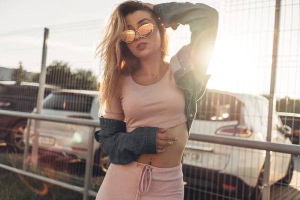 在街上穿着便装的年轻漂亮女人的肖像 穿着粉红色衬衫和裤子 夏天的概念 放松时间 戴墨镜的女孩 享受城市日落 — 图库照片