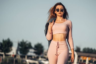 Genç ve güzel kadın sokakta rahat kıyafetler portresi. Pembe gömlek ve pantolon giymiş. Bahar, yaz konsepti. Zaman rahatla. Güneş gözlüklü kız. Şehir Günbatımı keyfini çıkarın.