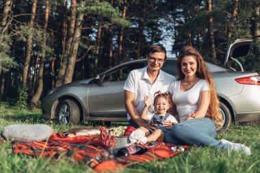 Üç kişi yaz zevk aile hafta sonu piknik kavramı, şehir dışında parkta eğleniyor onların küçük kızı ile genç çift