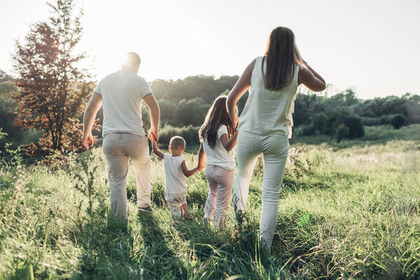 Adult couple with their little children having picnic in the Park Outside the City, Family Weekend Concept, Four People Enjoying Summer