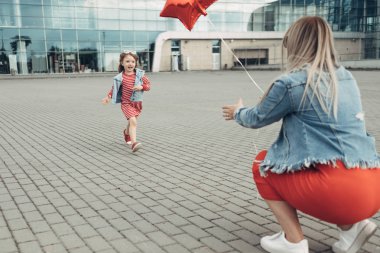 Güzel genç anne küçük şık kızı ile şehir yürüyor