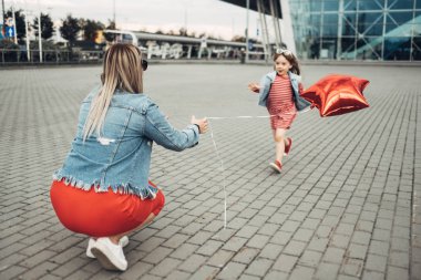 Güzel genç anne küçük şık kızı ile şehir yürüyor