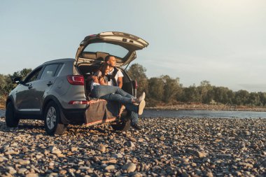 Mutlu çift Roadtrip Suv arabada batımına üzerinde