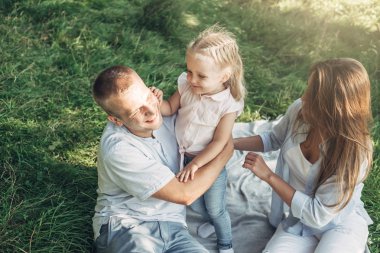 Üç kişi yaz zevk aile hafta sonu piknik kavramı, şehir dışında parkta eğleniyor onların küçük kızı ile genç yetişkin çift