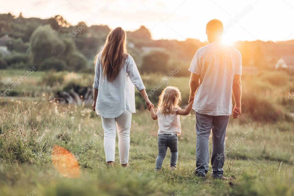 Young Adult Couple with Their Little Daughter Having Fun in the Park Outside the City, Family Weekend Picnic Concept, Three People Enjoying Summer