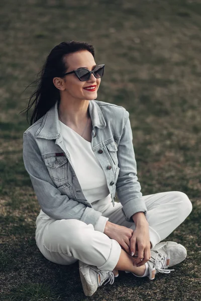 Hermosa chica morena en gafas de sol pantalones blancos y Jeans chaqueta, lápiz labial rojo —  Fotos de Stock