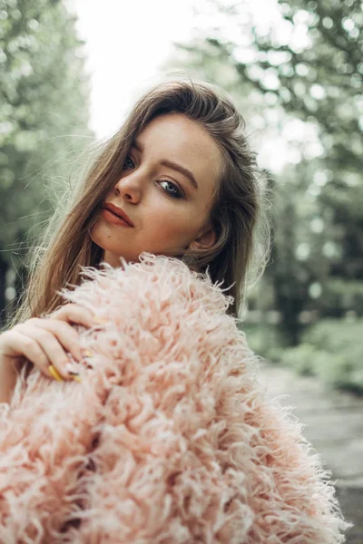 Porträtt av en snygg flicka i rosa päls poserar på gatan — Stockfoto