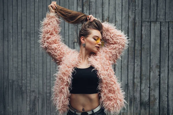Портрет одной стильной девушки в розовом пальто и современных желтых футболках на улице — стоковое фото
