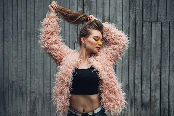 Portrait d'une fille élégante en manteau rose et lunettes de soleil jaune moderne posant sur la rue — Photo