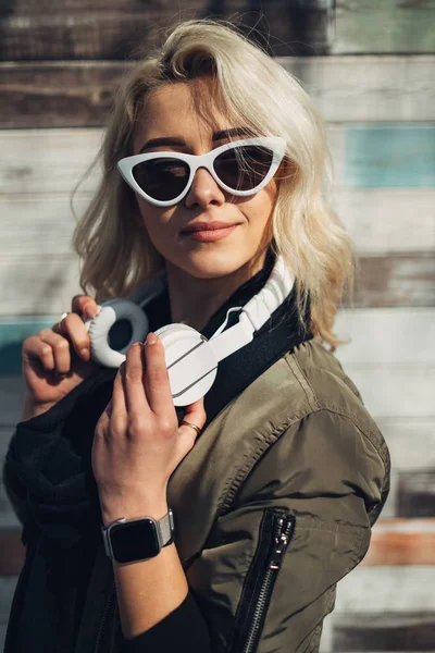 Menina loira bonita em Green Jacket ouvir música em fones de ouvido — Fotografia de Stock