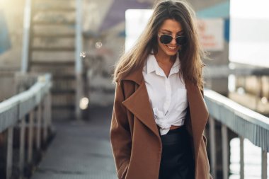 Gün batımında Bahar Plajı'nda Yürüyen Paltolu Güzel Genç Şık Kız