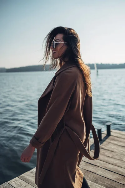 Vacker ung snygg tjej i pälsen promenader i vår stranden vid solnedgången — Stockfoto