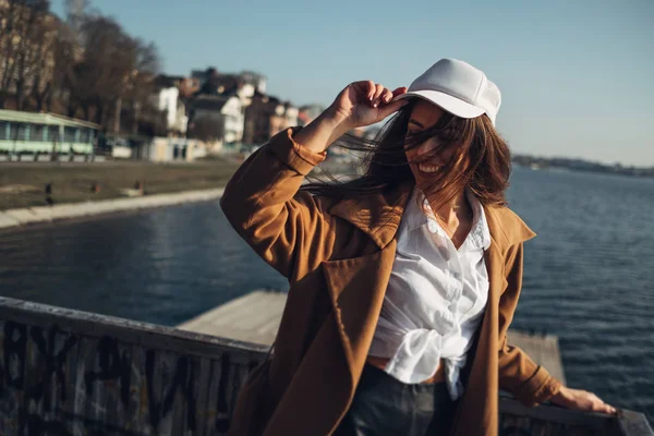 Schöne junge stilvolle Mädchen im Mantel zu Fuß im Frühling Strand bei Sonnenuntergang — Stockfoto