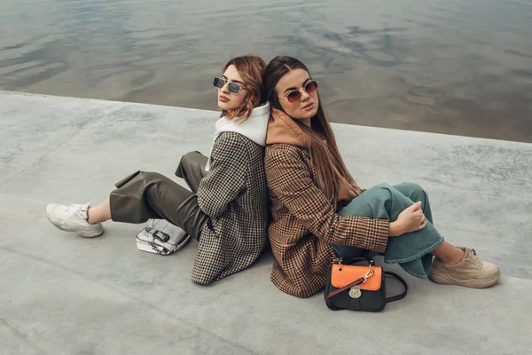 Retrato de dos chicas de moda, Mejores amigos al aire libre, Usando chaqueta elegante, Caminando cerca del lago —  Fotos de Stock