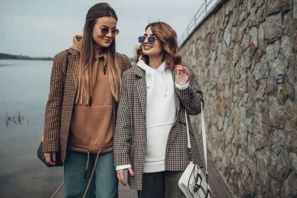 Портрет двух девушек из моды, лучшие друзья на открытом воздухе, в стильной куртке, прогулки у озера — стоковое фото