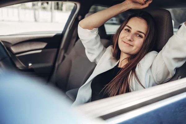 Модная стильная девушка-водитель в белом костюме сидит в машине — стоковое фото