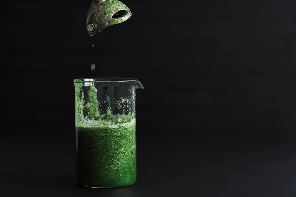 一只绿色的冰沙鸡尾酒正站在黑桌上 — 图库照片