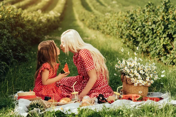 赤い水玉のドレスのように彼女の小さな娘と若いお母さん フィールドでのピクニックで楽しい時間を持っています 母親と子供時代のコンセプト — ストック写真