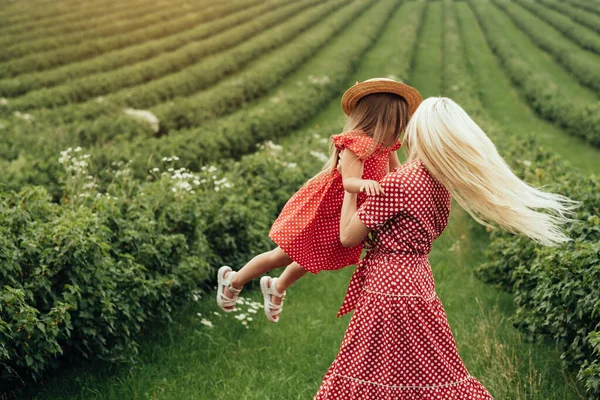 赤い水玉のドレスのように彼女の小さな娘と若いお母さん 街の外のフィールドで楽しい時間を持っています 母親と子供時代のコンセプト — ストック写真